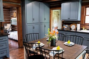 A log cabin interior with a dining area, kitchen, and a bed. - Fully Restored Cabin with Private Hut-Tub in Livingston, Texas (Livingston)
