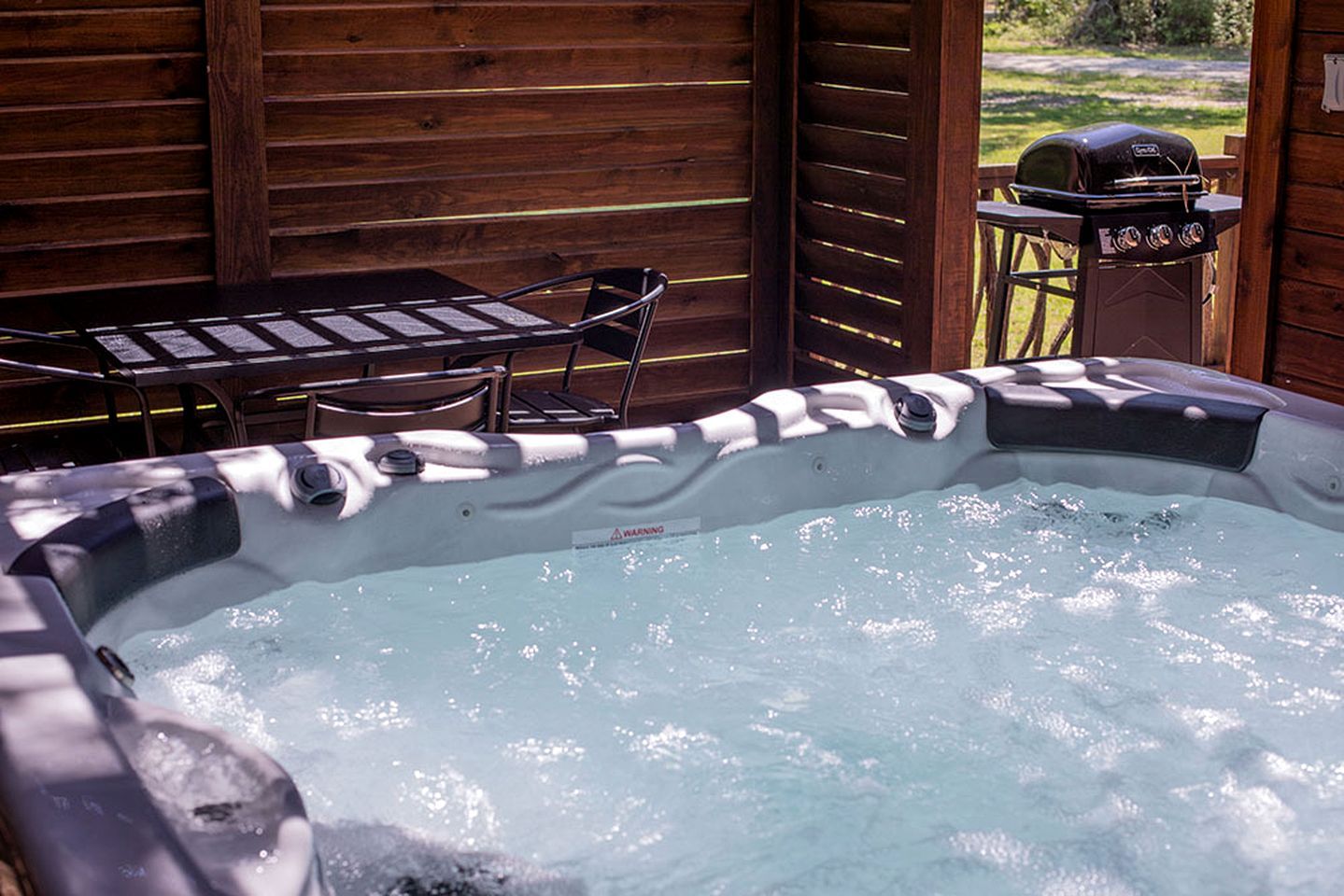 Un bain à remous avec une terrasse en bois et un barbecue.