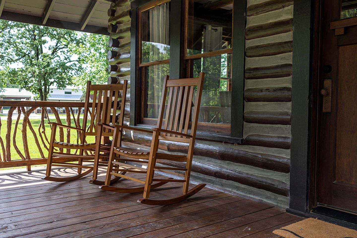 A log cabin with a porch, rocking chairs, and a table.