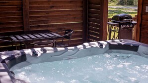 Un jacuzzi con terraza de madera y una parrilla.