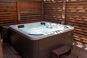 A hot tub in an outdoor wooden deck area. - Fully Restored Cabin with Private Hut-Tub in Livingston, Texas (Livingston)