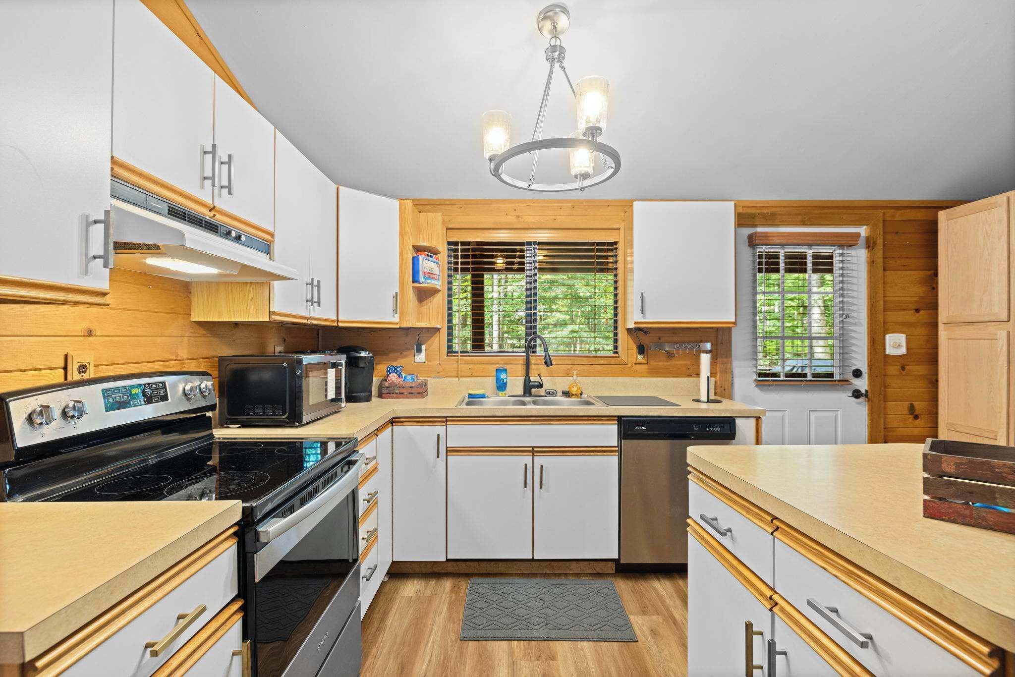 A compact kitchen with a microwave, stove, sink, and wooden cabinets.