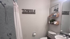 Een badkamer met douche, toilet, wastafel en handdoekhouder.