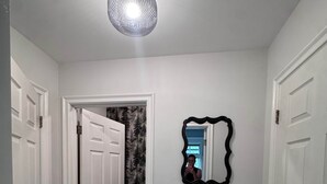 Un couloir avec des portes blanches, un sol carrelé et un miroir fixé au mur.