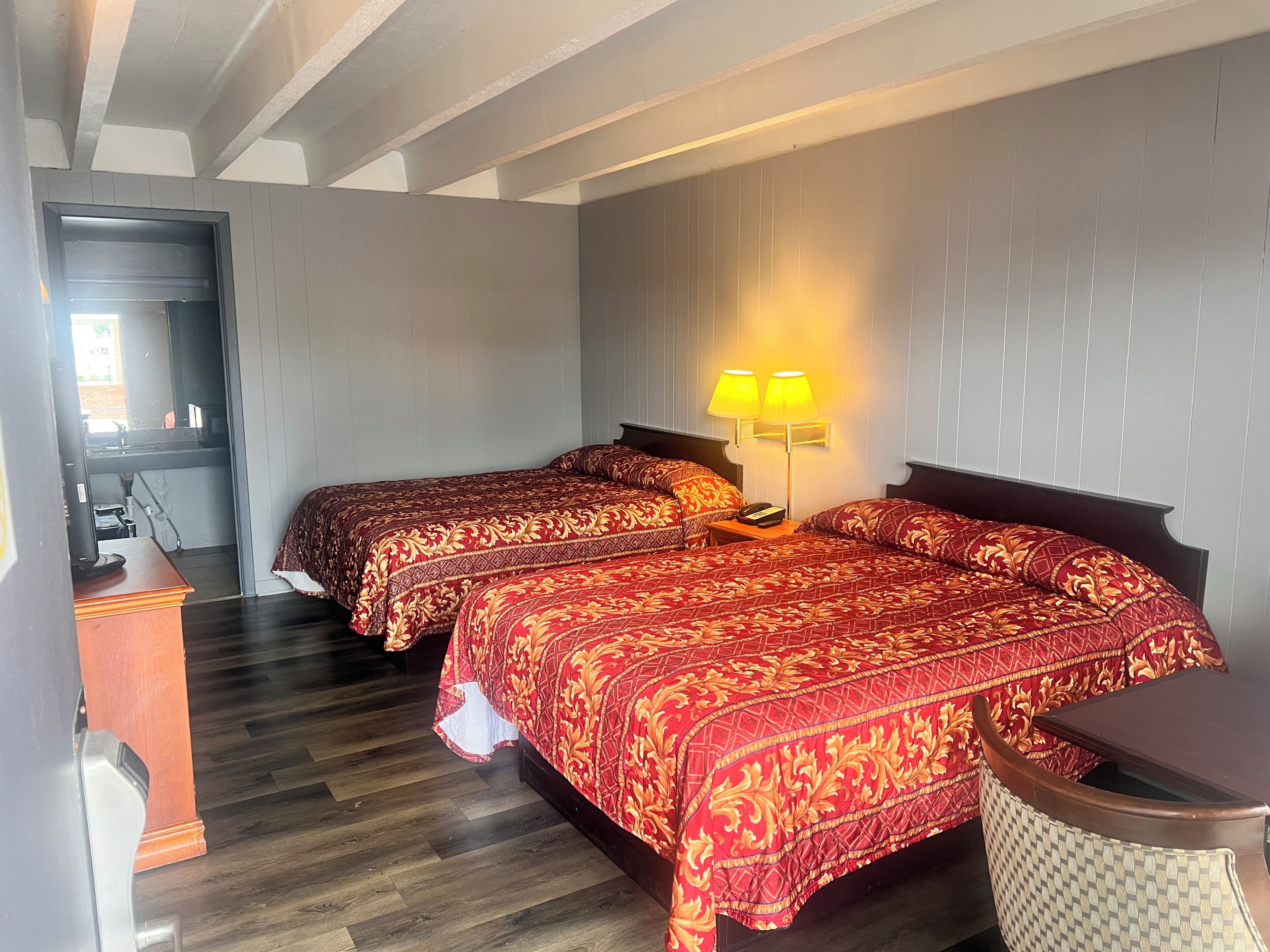 Een hotelkamer met twee bedden, een bureau, een stoel en een lamp.