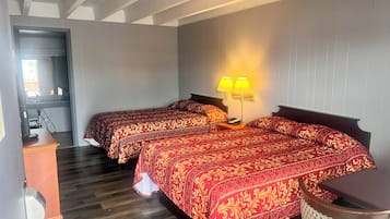Ein Hotelzimmer mit zwei Betten, einem Schreibtisch, einem Stuhl und einer Lampe.