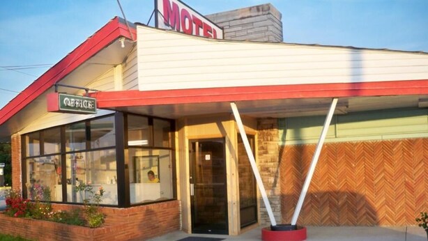 Un motel con un cartel con la letra 'Q', fachada de ladrillo y pared con patrón de espiga.