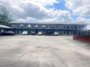 A motel with a row of rooms, a parking lot, and a clear sky. - Scottish Inns Morristown (Morristown)