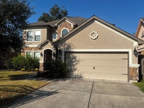 A two-story house with a stone facade, a garage, and a driveway. - Charming en-suite bedroom in Houston with all bill included. (Houston)