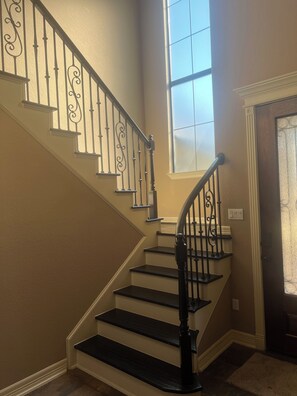 A staircase with ornate black railings, beige walls, and a window with frosted glass. - Charming en-suite bedroom in Houston with all bill included. (Houston)