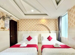 A hotel room with two beds, a ceiling fan, a patterned wall, and a window with curtains. - Song Xanh Hotel  (Ho Chi Minh City)