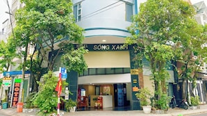 A hotel with a curved facade, a visible entrance, and a sign reading 'HOTEL SŎNG XANH'. - Song Xanh Hotel  (Ho Chi Minh City)