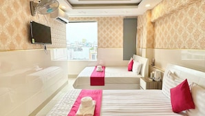 A hotel room with two beds, a TV, a ceiling fan, and a window with a city view. - Song Xanh Hotel  (Ho Chi Minh City)
