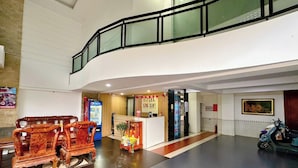 A hotel lobby with a reception desk, a Pepsi refrigerator, a wooden bench, and a scooter. - Song Xanh Hotel  (Ho Chi Minh City)