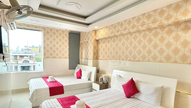 A hotel room with two beds, a large window, and a view of the cityscape. - Song Xanh Hotel  (Ho Chi Minh City)