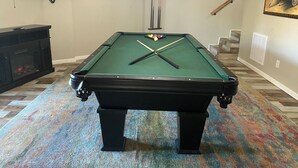 A pool table with a green felt surface, a fireplace, a television, and a framed picture on the wall. - Welcome to the Round Roost- 3 story+sleeps 16+Lake Ham+grill+decks+game room (Hot Springs)