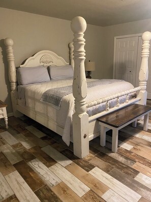Una cama con estructura de madera y un banco al pie.