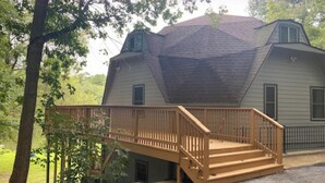 A house with a steeply pitched roof, a wooden deck with stairs, and a fenced yard. - Welcome to the Round Roost- 3 story+sleeps 16+Lake Ham+grill+decks+game room (Hot Springs)