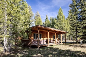 A wooden cabin with a porch, surrounded by tall pine trees. - Mountain Cabin Near Yellowstone with Scenic Views, West Yellowstone, Montana (West Yellowstone)