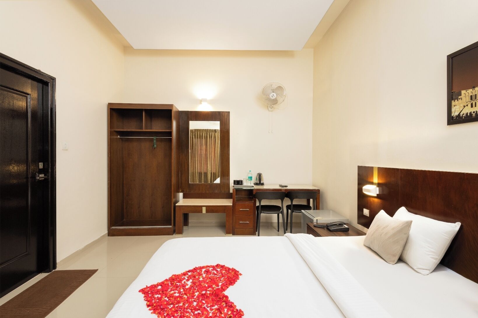 A hotel room with a bed, a desk, a wardrobe, and a mirror.