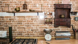 A kitchen with a brick wall, a gas stove, a scale, and wooden cabinets. - The Sicilian Farmhouse (Palmeri - Ferrante)