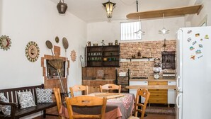 A kitchen with a brick backsplash, wooden furniture, and a white refrigerator with magnets. - The Sicilian Farmhouse (Palmeri - Ferrante)