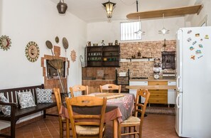 A kitchen with a brick backsplash, wooden furniture, and a white refrigerator with magnets. - The Sicilian Farmhouse (Palmeri - Ferrante)
