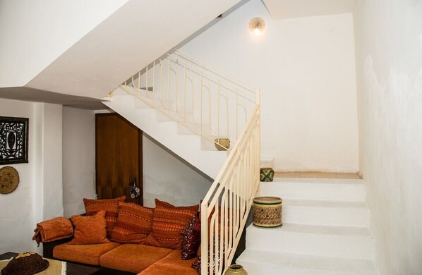 A staircase with a white railing, a sofa with patterned cushions, and a decorative wall piece. - The Sicilian Farmhouse (Palmeri - Ferrante)
