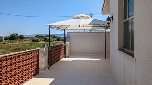 A balcony with a patterned fence, a tiled floor, and a white umbrella. - The Sicilian Farmhouse (Palmeri - Ferrante)