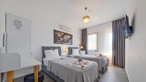 Ein Hotelzimmer mit zwei Betten, einem Schreibtisch, einem Stuhl, einer Karte an der Wand und einem angebauten Fernseher.