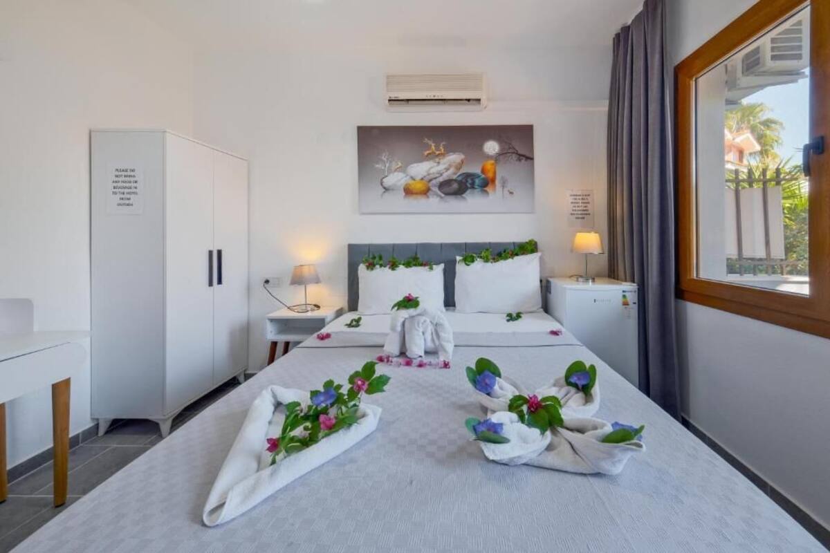 Habitación de hotel con cama, mesitas de noche, escritorio, armario y un cuadro en la pared.