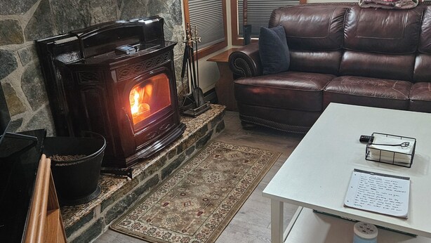 A cozy living room with a stone fireplace, leather sofa, and a white coffee table.