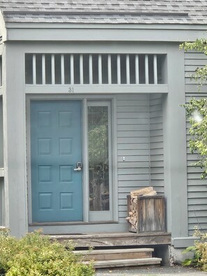 Ein Haus mit einer blauen Tür, der Hausnummer 31 und einer kleinen Veranda mit Treppen.