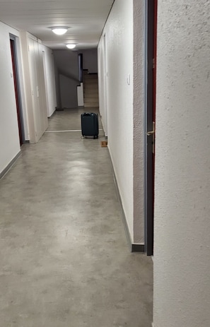 Ein langer, schmaler Flur mit einem Koffer in der Ferne, der zu einer Treppe führt.