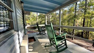 A covered porch with wooden flooring, a rocking chair, and a bench.