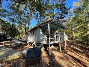 Eine Holzhütte mit Veranda und Picknicktisch, umgeben von Bäumen.
