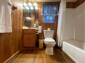 Un baño de madera con inodoro, lavabo y bañera.