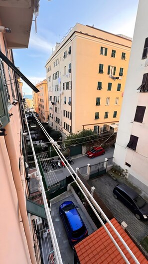 Ein mehrstöckiges Wohngebäude mit Balkonen, Blick auf die Straße und geparkten Autos.