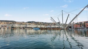 A waterfront view with a modern bridge structure, boats, and a cityscape in the background. - Apartment 'House Fede' with Sea View and Wi-Fi (Genoa)