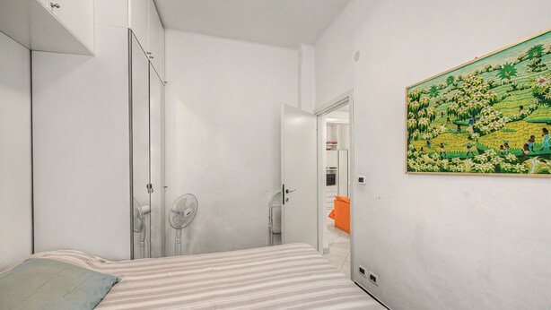 A bedroom with a bed, a fan, and a painting on the wall. - Apartment 'House Fede' with Sea View and Wi-Fi (Genoa)