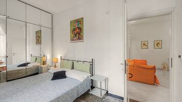 Une chambre d’hôtel avec deux lits, un grand miroir, un tableau et une porte donnant sur une autre pièce.