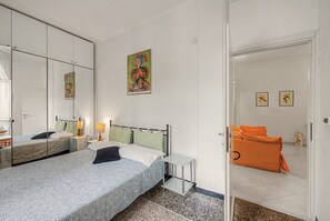 Una camera d'albergo con due letti, un grande specchio, un quadro e una porta che dà su un'altra stanza.