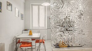 A dining area with a white table, orange chairs, and a yellow vase. - Apartment 'House Fede' with Sea View and Wi-Fi (Genoa)
