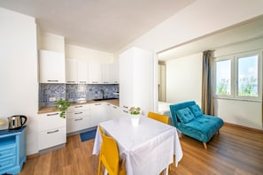 A modern kitchen with white cabinets, a blue backsplash, and a dining area with a white table and yellow chairs. - Ischia Apartment with seaview terrace for 4 people (ISCHIA)