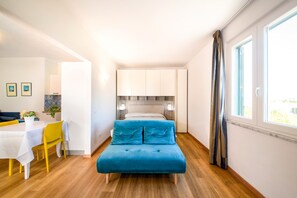 Un dormitorio con cama, mesitas de noche, una ventana y una zona de comedor con mesa y sillas.
