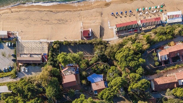 Vista aèria d'una zona residencial amb cases, una platja i un pàrquing.