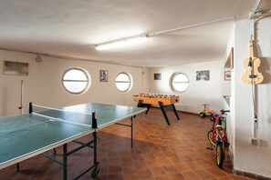 Une pièce équipée d’une table de ping-pong, d’un baby-foot, de vélos et d’un violon.