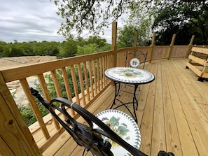 A wooden deck with a table and chairs, surrounded by a wooden railing. - Charming Conestoga Wagon Rental for Unforgettable Glamping in Mineral Wells, Texas (Mineral Wells)