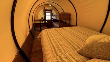 A tent with a bunk bed, a small table, and a chair.
