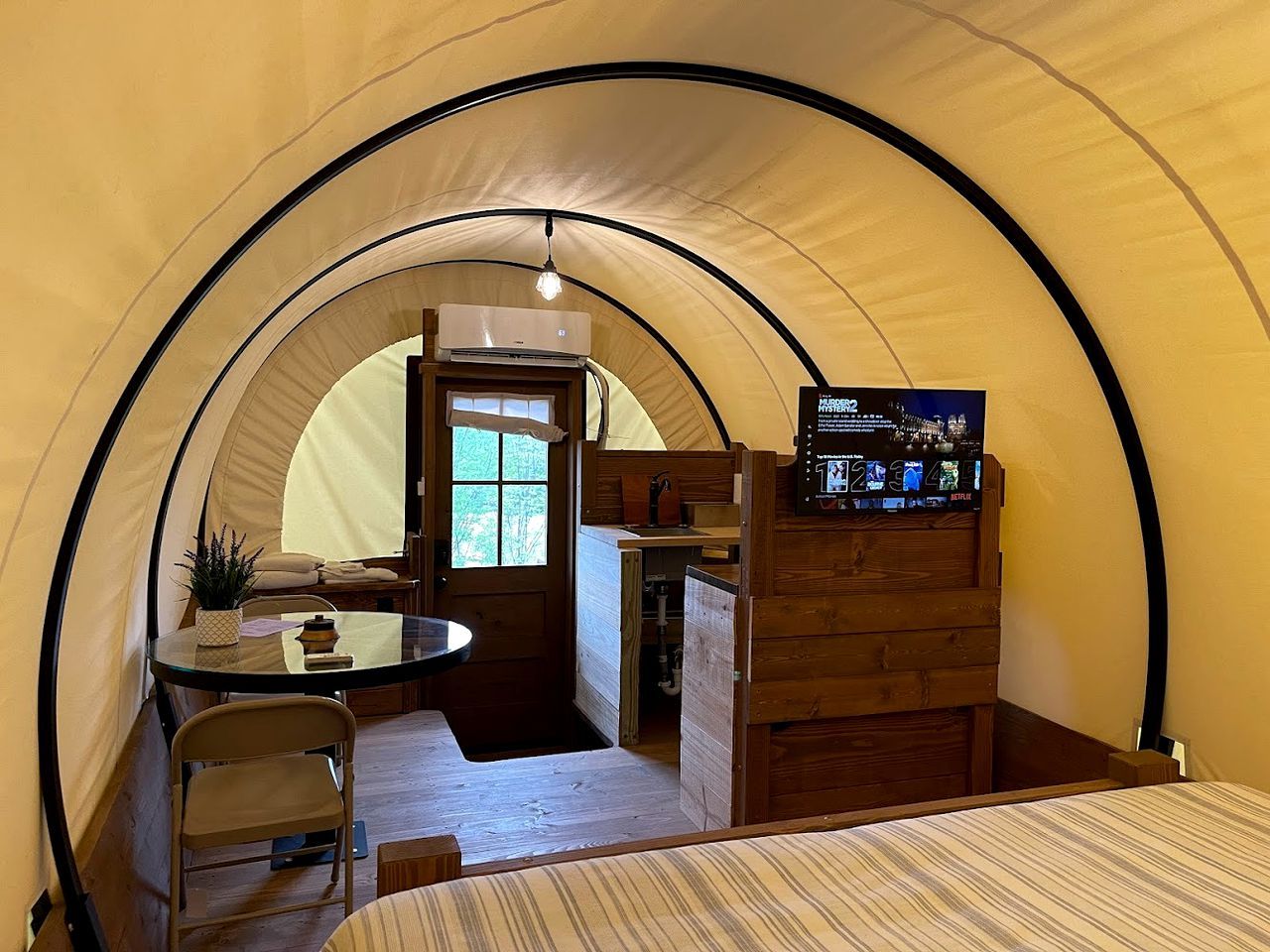 A tent with a kitchenette, a table, and a TV.